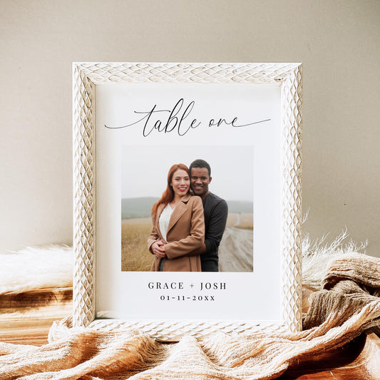 Table number card featuring the text &#39;table one&#39; in an elegant calligraphy script font, followed by a large photo of a couple, then their names and wedding date.