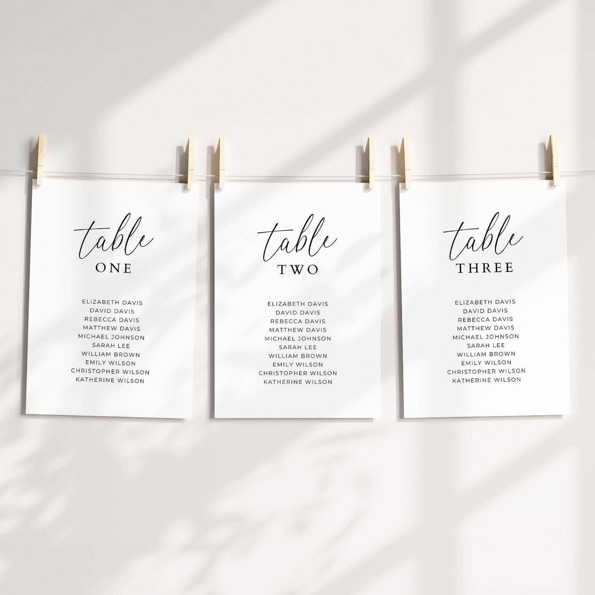 Table number cards, with 'table' in a script font followed by the number, with 10 guest names written below